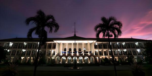 UGM campus building lit up at night with pink sky 